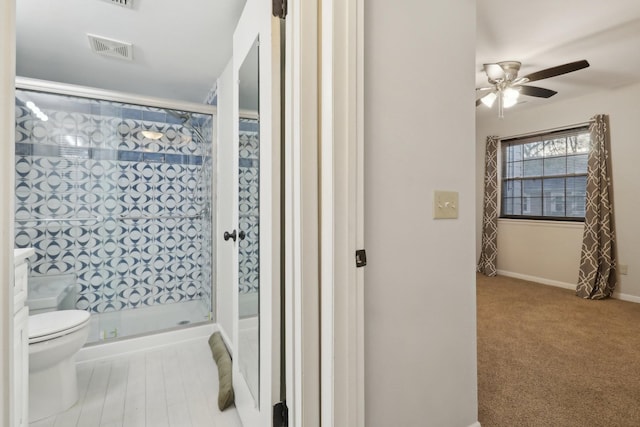 bathroom with a shower with shower door, ceiling fan, and toilet