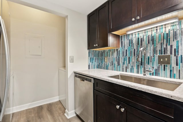 kitchen with sink, light stone counters, light wood-type flooring, stainless steel appliances, and decorative backsplash