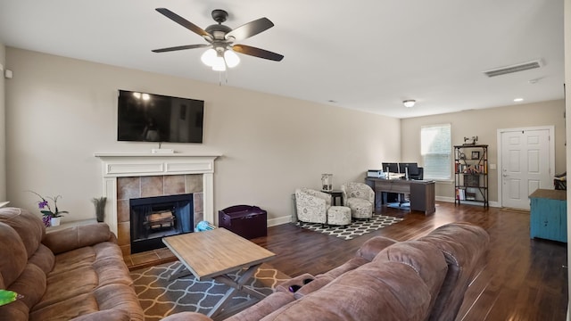 living room with ceiling fan, dark wood-type flooring, and a tile fireplace