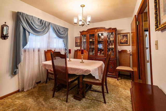 carpeted dining room with an inviting chandelier and baseboards