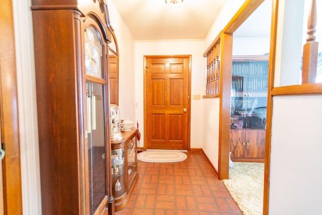 hall featuring brick floor and baseboards