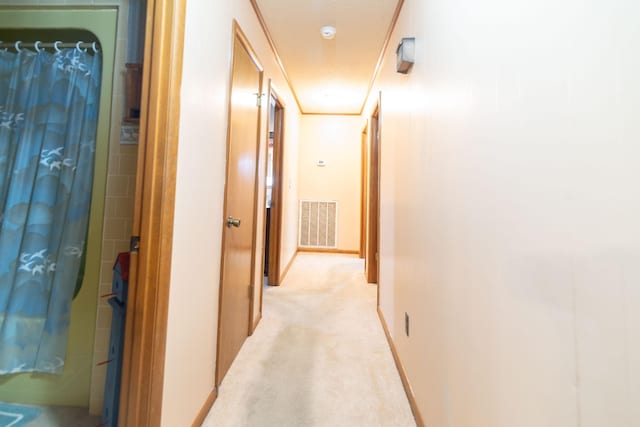 corridor featuring light carpet, baseboards, and visible vents