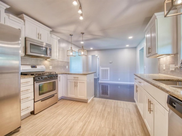 kitchen with decorative backsplash, appliances with stainless steel finishes, sink, pendant lighting, and white cabinets