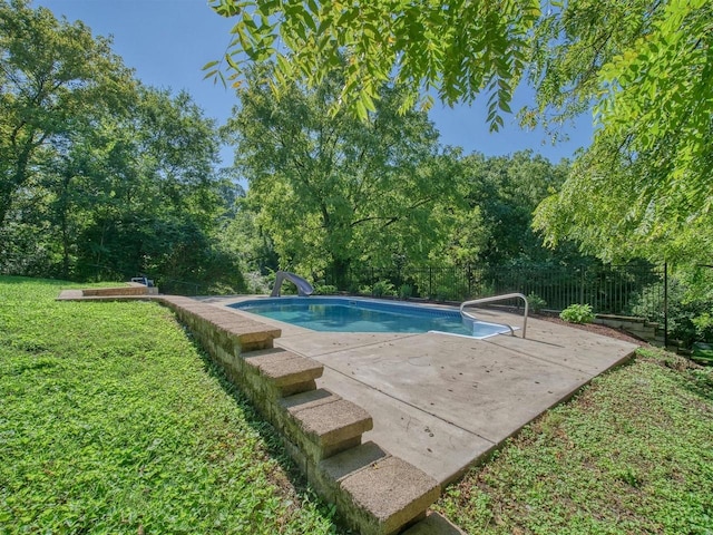 view of swimming pool with a lawn, a patio, and a water slide