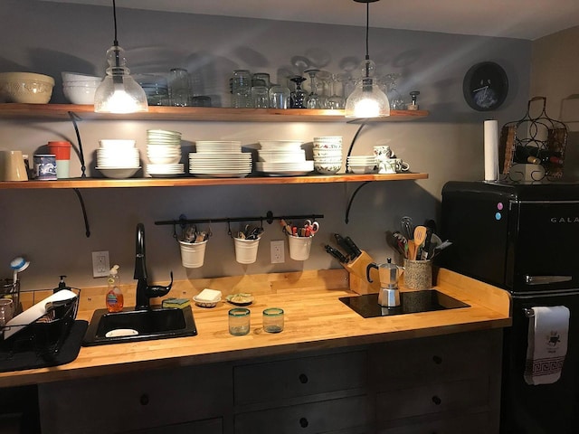 bar with pendant lighting, black electric cooktop, sink, and wooden counters