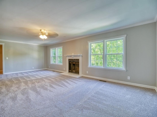 unfurnished living room featuring light carpet, ornamental molding, ceiling fan, and a healthy amount of sunlight