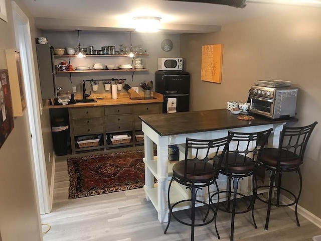 kitchen featuring wooden counters, hardwood / wood-style floors, fridge, and a breakfast bar area