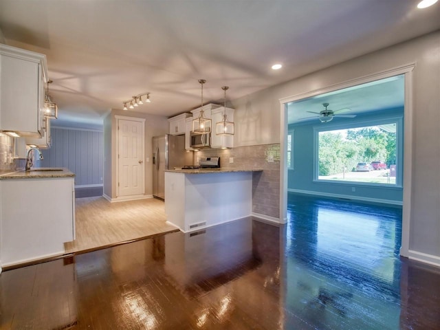 kitchen with stainless steel appliances, white cabinetry, sink, and pendant lighting