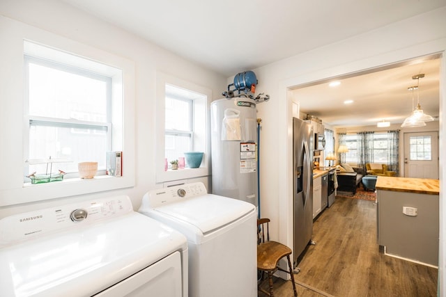 clothes washing area with separate washer and dryer, dark wood-type flooring, and water heater