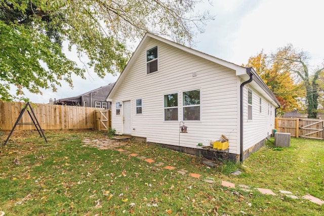 rear view of property with central AC unit and a yard