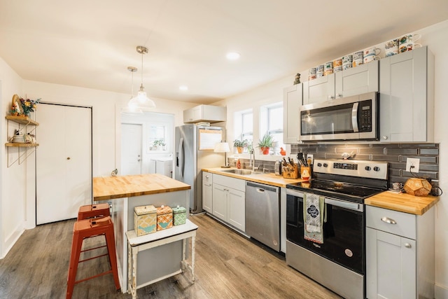 kitchen with independent washer and dryer, a sink, tasteful backsplash, stainless steel appliances, and wooden counters