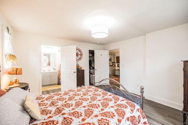 bedroom with a closet, ensuite bath, baseboards, and wood finished floors