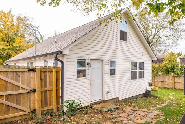 rear view of property featuring a gate, a shingled roof, and fence