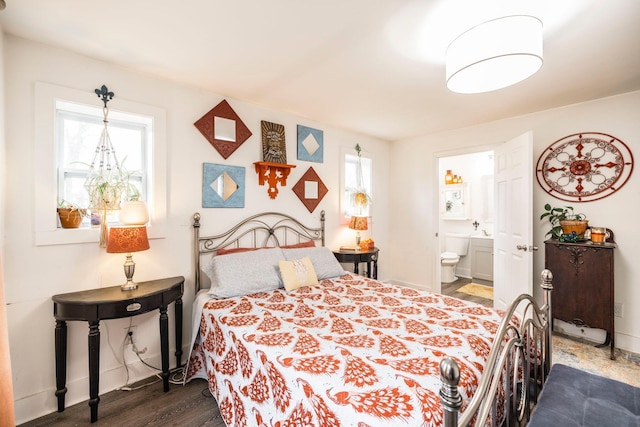 bedroom with baseboards, dark wood-style flooring, and connected bathroom