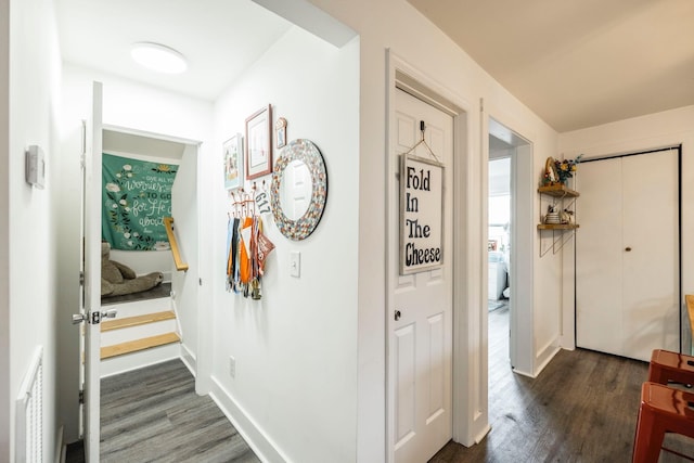 hallway with visible vents, baseboards, dark wood-type flooring, and stairs