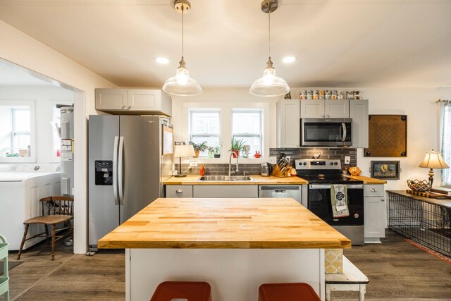 kitchen featuring backsplash, dark wood-type flooring, butcher block countertops, stainless steel appliances, and a sink