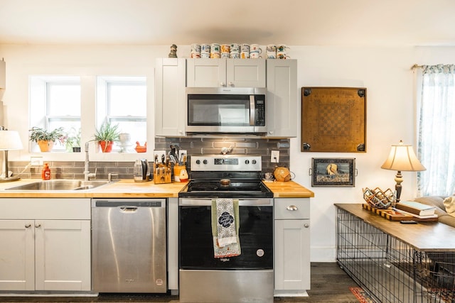 kitchen featuring wooden counters, dark hardwood / wood-style flooring, tasteful backsplash, stainless steel appliances, and sink