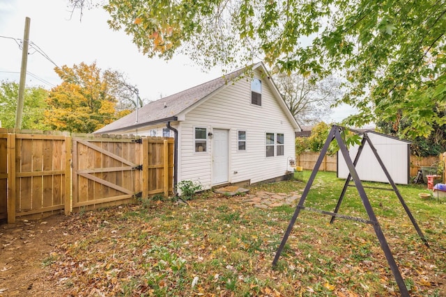 back of house with a yard, an outbuilding, a fenced backyard, and a gate