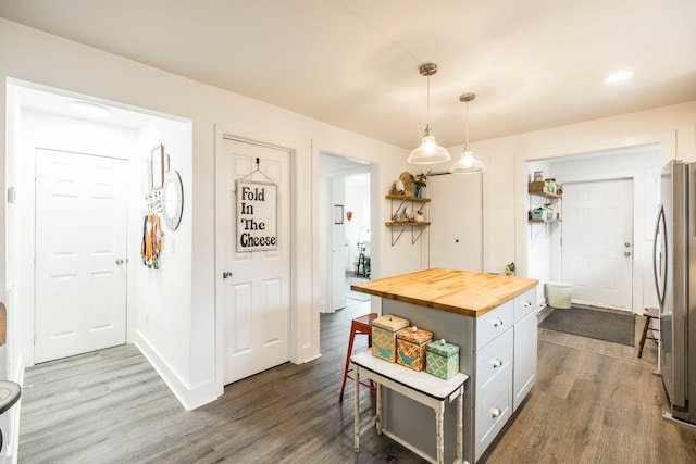 kitchen featuring open shelves, freestanding refrigerator, dark wood-type flooring, pendant lighting, and butcher block counters