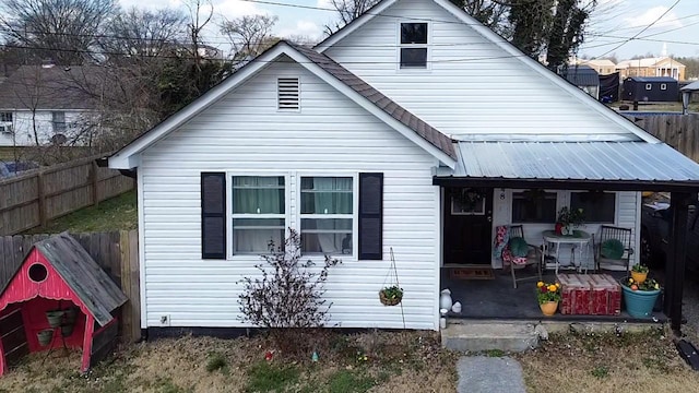 view of front facade featuring a porch, fence, and metal roof