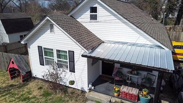 back of property featuring metal roof, a patio, roof with shingles, and a fenced backyard