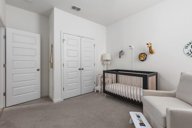 bedroom featuring a crib, light carpet, and a closet