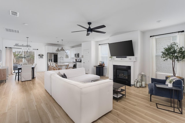 living room featuring ceiling fan, a healthy amount of sunlight, sink, and light hardwood / wood-style flooring