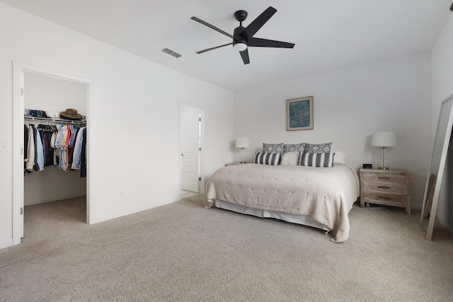 carpeted bedroom featuring ceiling fan, a spacious closet, and a closet