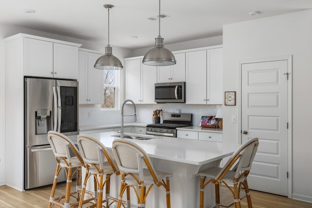 kitchen featuring a breakfast bar, light wood-type flooring, white cabinetry, and appliances with stainless steel finishes