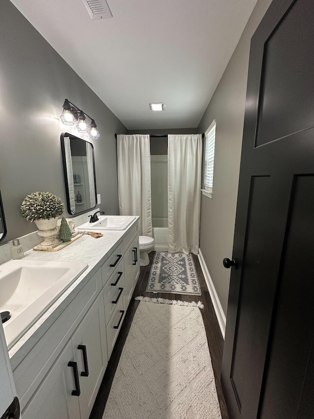 full bathroom with hardwood / wood-style floors, shower / bath combination with curtain, vanity, and toilet