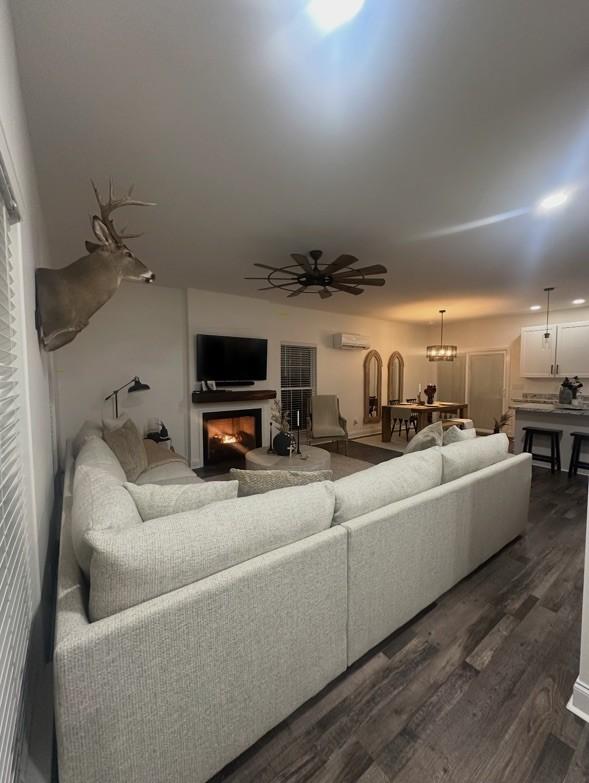 living room featuring dark hardwood / wood-style floors, ceiling fan, and a wall mounted AC