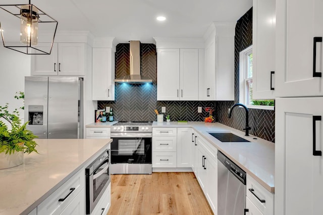 kitchen featuring sink, white cabinets, wall chimney range hood, and appliances with stainless steel finishes