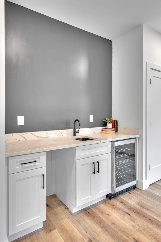 bar with white cabinetry, wine cooler, light hardwood / wood-style floors, and sink