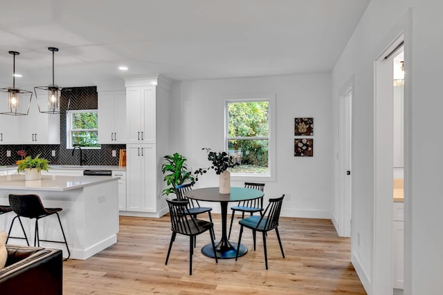 kitchen featuring a wealth of natural light, white cabinetry, light hardwood / wood-style flooring, and pendant lighting