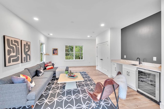 living room featuring wine cooler, sink, and light hardwood / wood-style floors