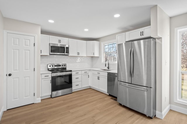 kitchen with backsplash, white cabinetry, sink, and stainless steel appliances