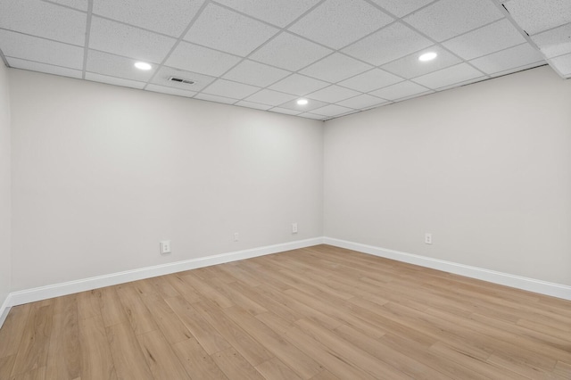 spare room featuring a paneled ceiling and light wood-type flooring