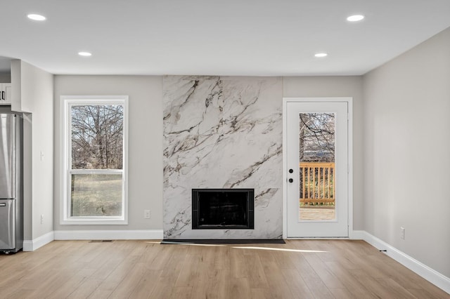 unfurnished living room featuring a high end fireplace and light wood-type flooring