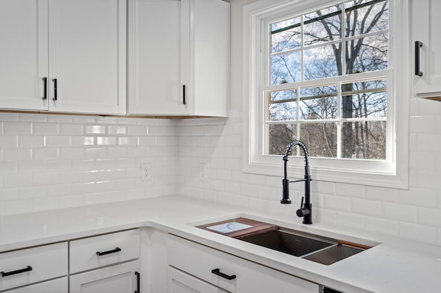 kitchen featuring decorative backsplash, white cabinetry, and sink