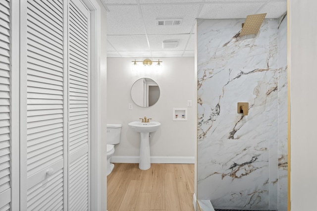 bathroom featuring toilet, a shower, a drop ceiling, and hardwood / wood-style flooring