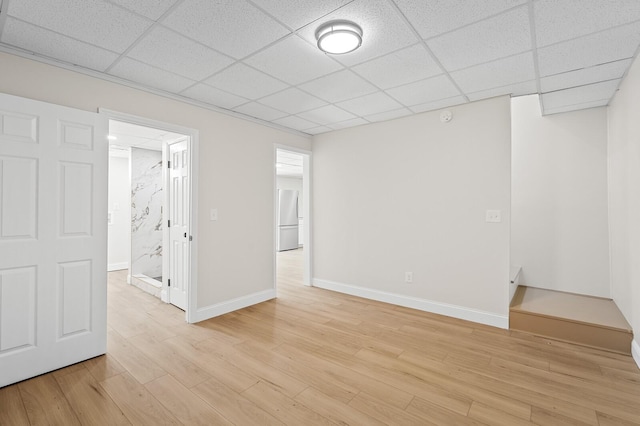 spare room featuring light wood-type flooring and a drop ceiling