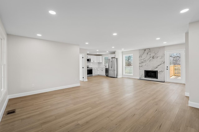 unfurnished living room with a premium fireplace and light hardwood / wood-style floors