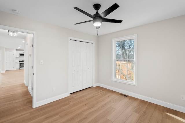 unfurnished bedroom featuring ceiling fan, light wood-type flooring, and a closet