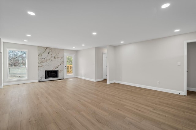 unfurnished living room featuring a high end fireplace and light wood-type flooring