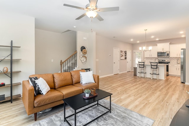 living room featuring light hardwood / wood-style floors and ceiling fan with notable chandelier