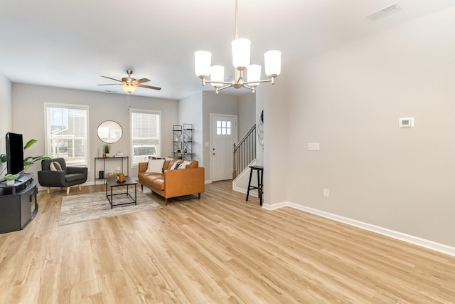 living room with ceiling fan with notable chandelier and light hardwood / wood-style floors