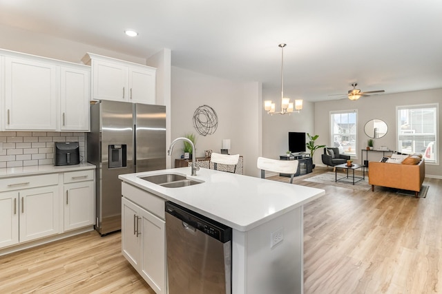 kitchen featuring an island with sink, ceiling fan with notable chandelier, white cabinets, appliances with stainless steel finishes, and sink