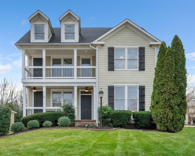 view of front of property with covered porch, a balcony, and a front lawn