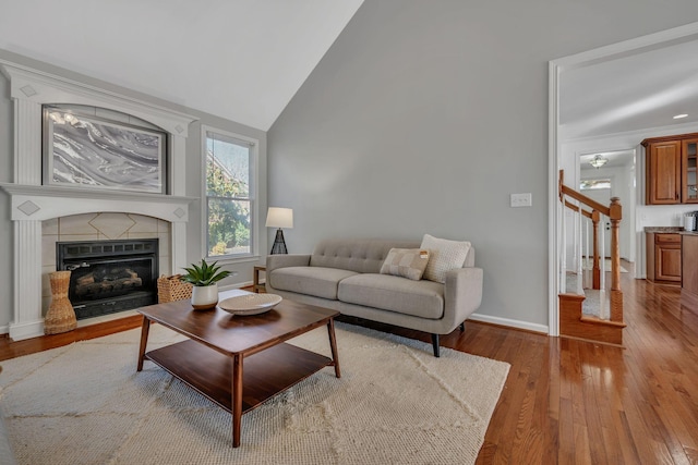 living room with a tile fireplace, light hardwood / wood-style floors, and lofted ceiling