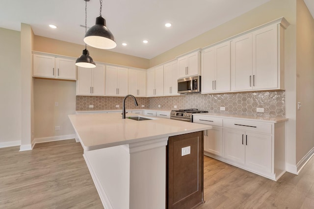 kitchen with pendant lighting, white cabinets, a center island with sink, sink, and appliances with stainless steel finishes